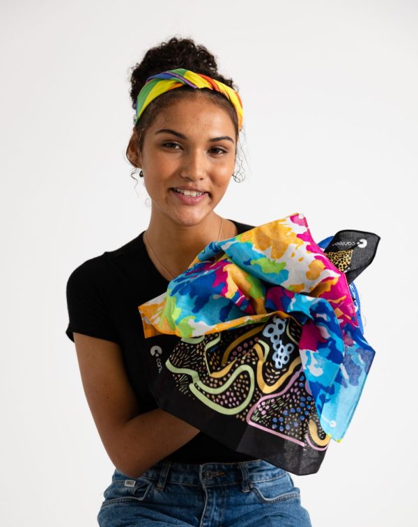 A person wearing a bandanna holding a Tie Dye bandanna