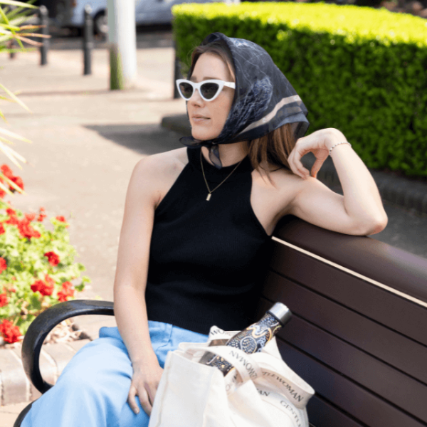 a girl sitting on a park bench wearing the canteen East of Sun, West of Moon bandanna